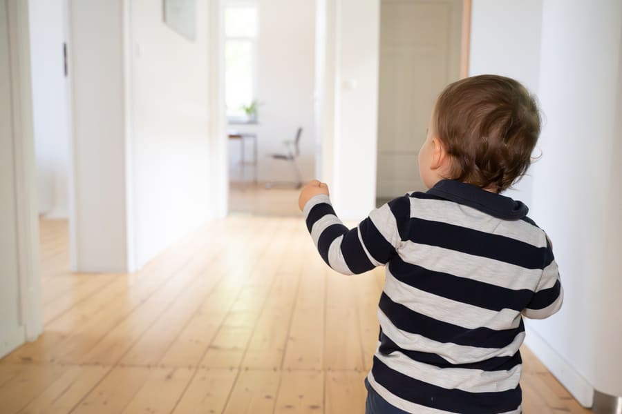 Ein kleiner Junge läuft fröhlich über den hellen und großzügigen Flur der Kinderosteopathie Praxis